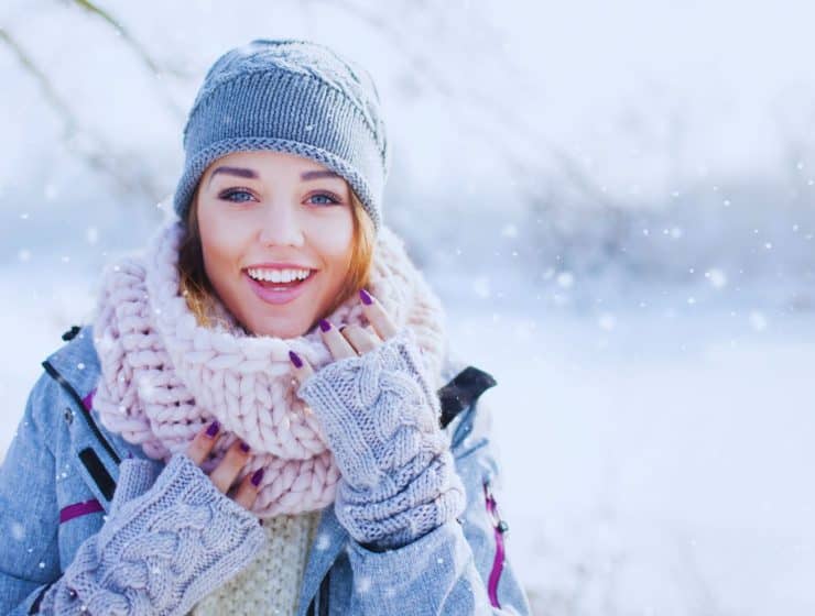 une-femme-souriante-vetue-dune-tenue-dhiver-ideale-avec-un-manteau-elegant-un-bonnet-en-laine-et-des-gants-se-promene-dans-un-paysage-enneige-elle-est-prete-a-affronter-le-froid-avec-style-et