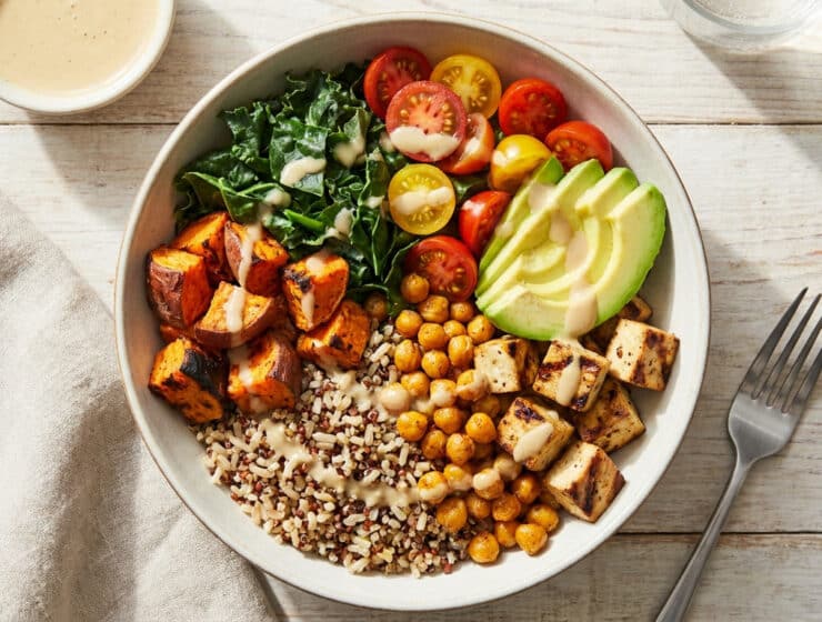 Un bol coloré composé de quinoa, pois chiches, tofu, patates douces, avocat, tomates cerises et chou kale.