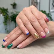 Mains avec une french manucure aux bouts colorés et métallisés, et un ongle entièrement doré.