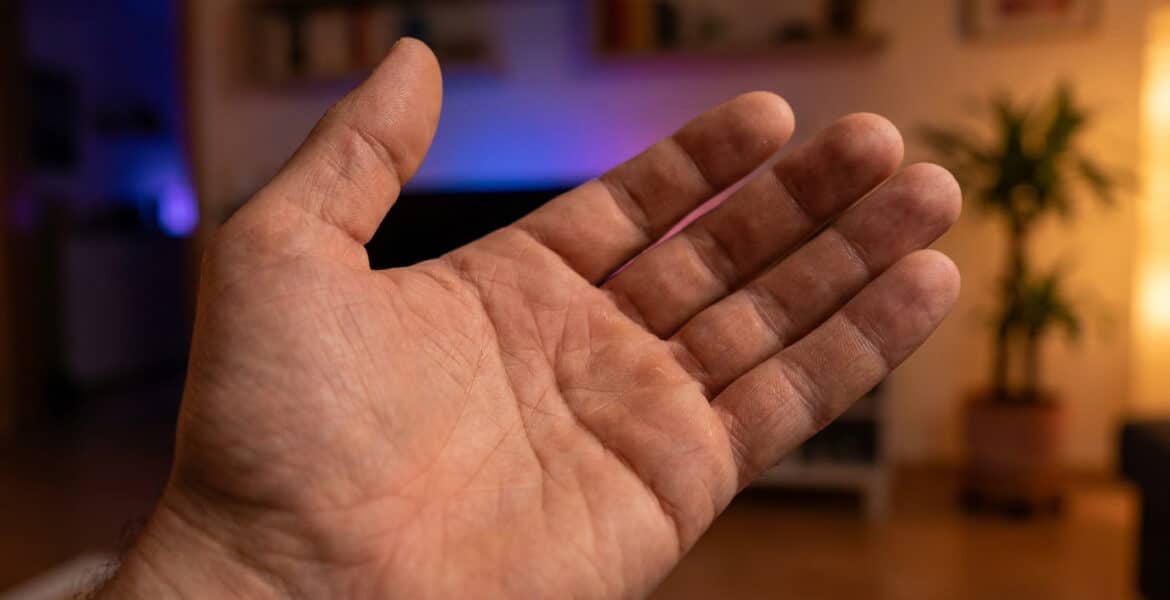 Une paume de main ouverte présentée devant un arrière-plan flou de salon.