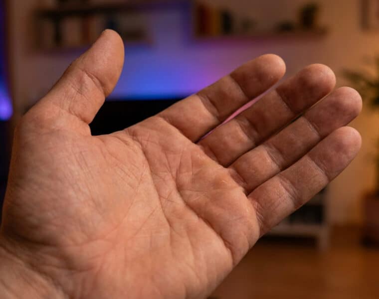 Une paume de main ouverte présentée devant un arrière-plan flou de salon.
