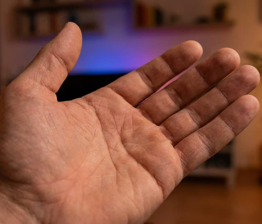 Une paume de main ouverte présentée devant un arrière-plan flou de salon.